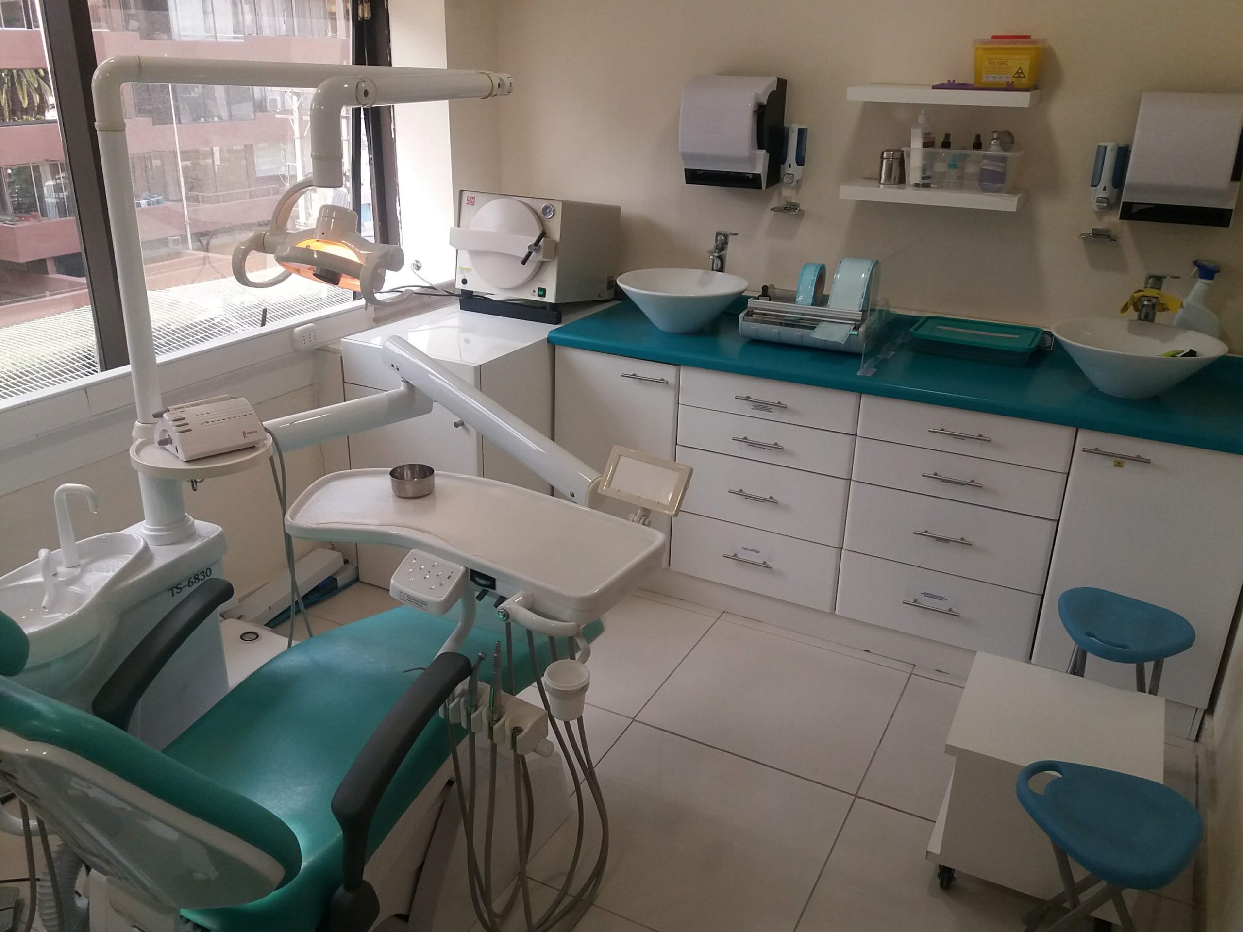Clinica Dental con su mobiliario para guardar insumos e instrumenta y su slilón dental de color blanco y verde.